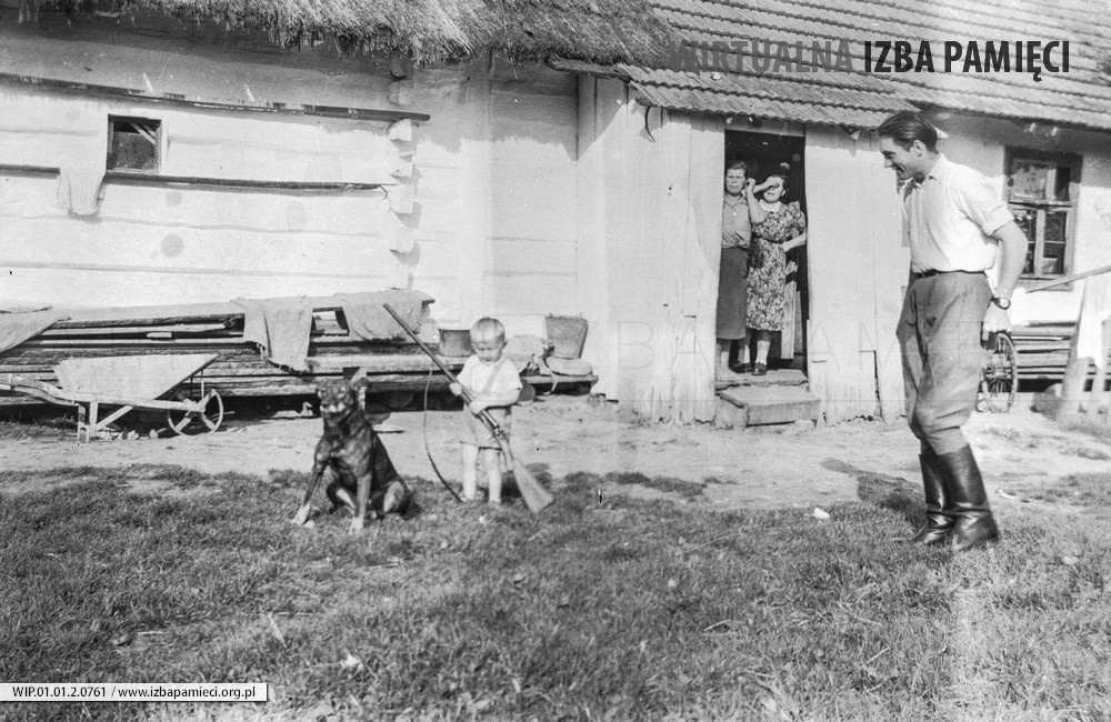 Lata 50. XX wieku. Dziecko ze strzelbą i psem pod okiem gajowego