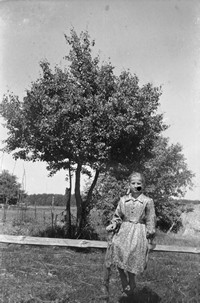 Lata 60. XX wieku. Aniela Hubacz siedzi na żerdzi okalającej pole