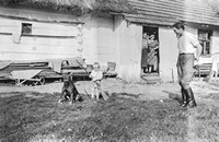Lata 50. XX wieku. Dziecko ze strzelbą i psem pod okiem gajowego