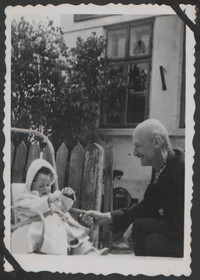 1950. Lubaczów. Barbara Gutowska w wózku z dziadkiem Władysławem Ruebenbauerem przed domem.